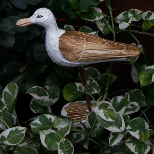 Wooden seagull amongst leaves